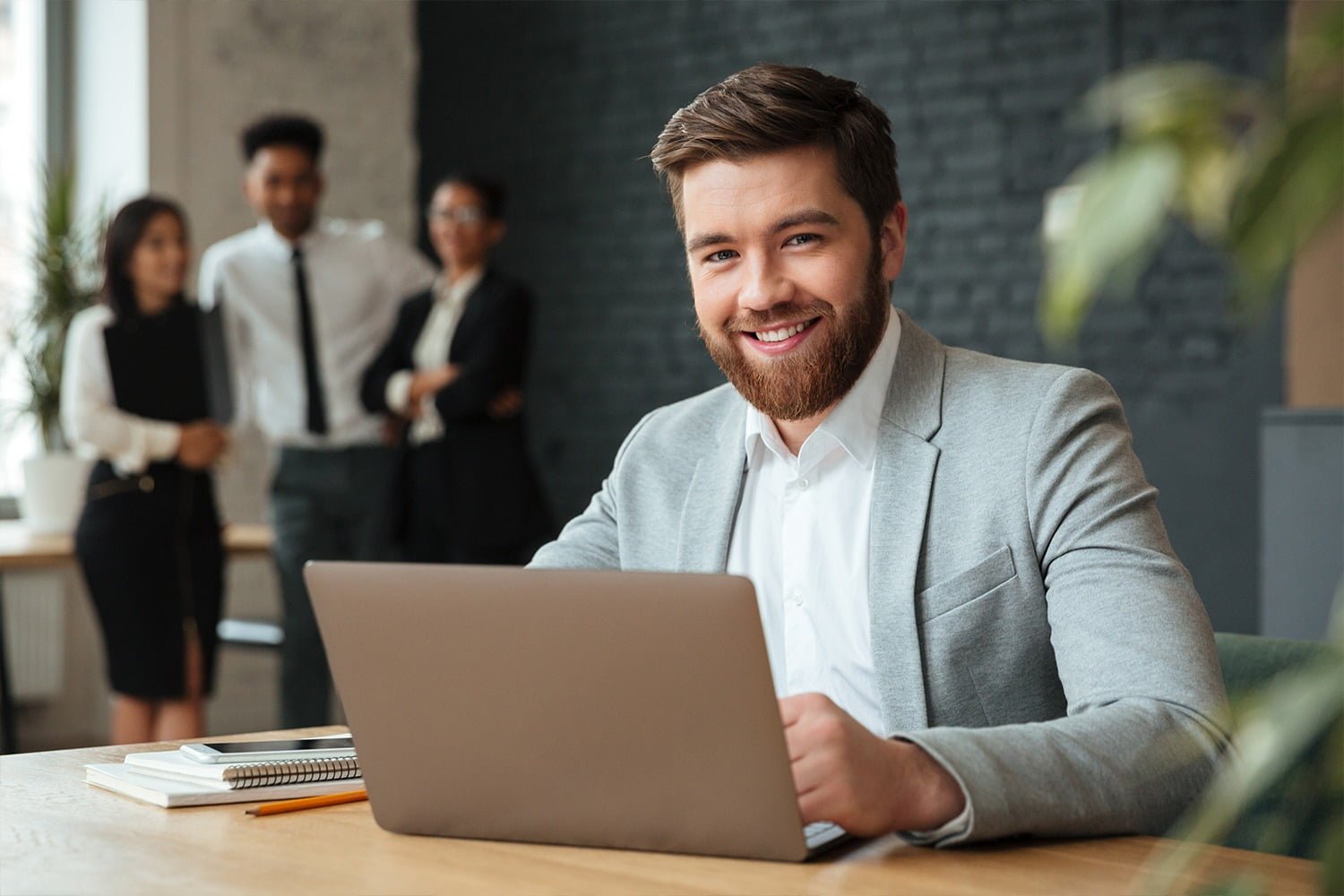 African American male grins at camera, indicates at copy space, advertises something. Happy black man points with fore fiinger, has happy expression, isolated over pink background. Look here!